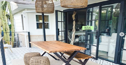 The view of a balcony with a tables other fixtures including a door from Pinky’s Iron Doors exterior steel door collection.
