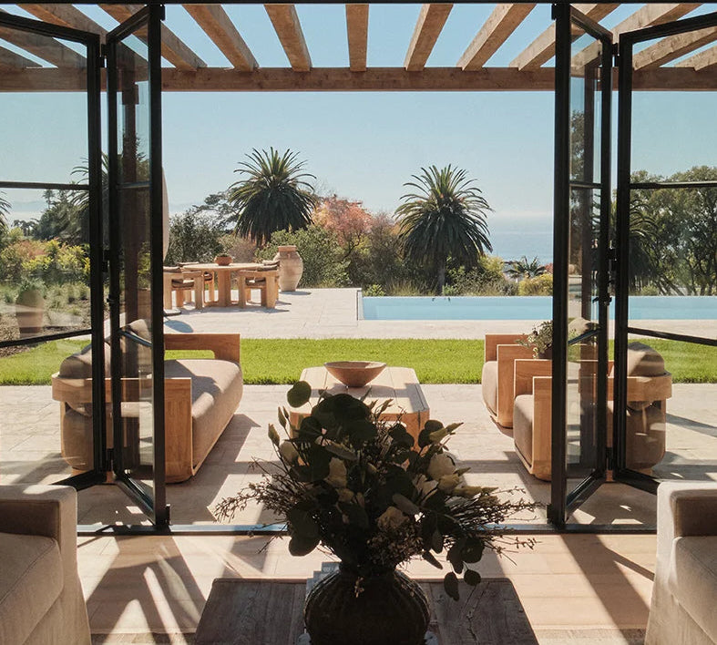 View of green seaside garden through center split steel bi-fold doors.
