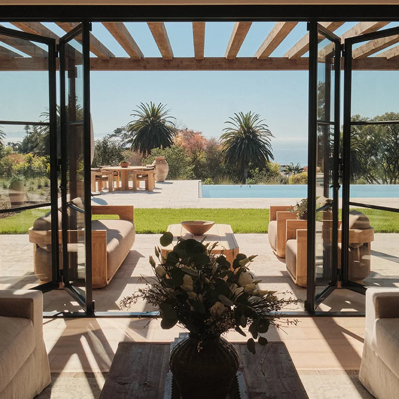 View of green seaside garden through center split steel bi-fold doors.