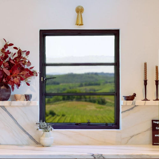 Black-framed steel window with horizontal panes in a white wall, showing a clear view of green rolling hills outside.