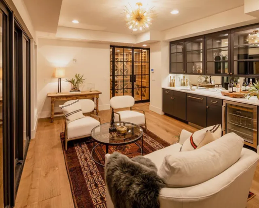 A home interior with wooden floors, white sofas, and a rug.