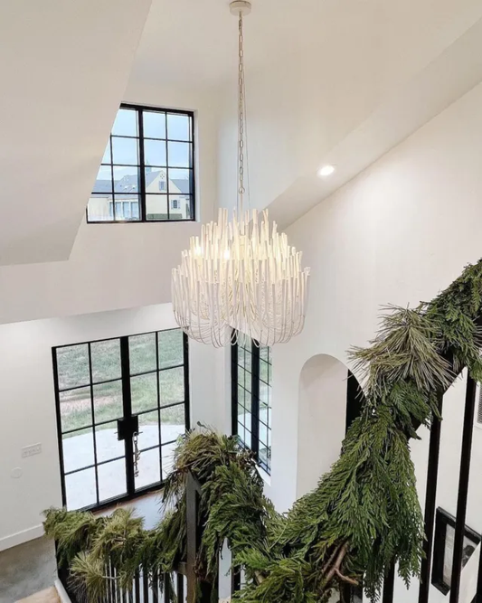 A home interior with a white chandelier and black steel doors.