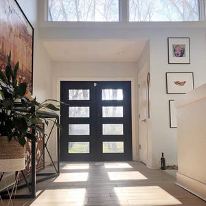 Double entryway doors made with a thick iron and steel frame and a full panel of glass behind 3 horizontal bars on each door. Doors are thermally broken to protect from extreme weather.