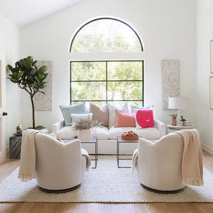 A brightly lit sunny living room with sofas and chairs and an arch top fixed window