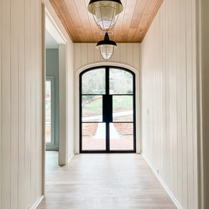 Gently curving arch top doors in a bright entry hallway with wood paneling