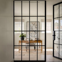 Load image into Gallery viewer, An artsy home office seen through an interior glass and steel wall partition and steel door