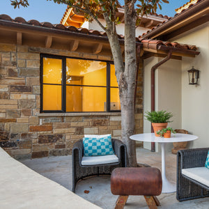 Landscape casement windows with a fixed panel in the middle looking out on a cozy Spanish style patio