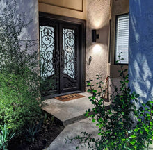 Load image into Gallery viewer, Double entryway doors with a thick steel and iron frame, two large windows behind an intricate iron pattern, and a curved kickplate. Doors are thermally broken to protect from extreme weather.