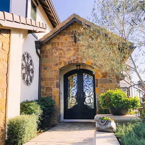 Double arched iron doors with intricate scrollwork design in natural stone entryway.