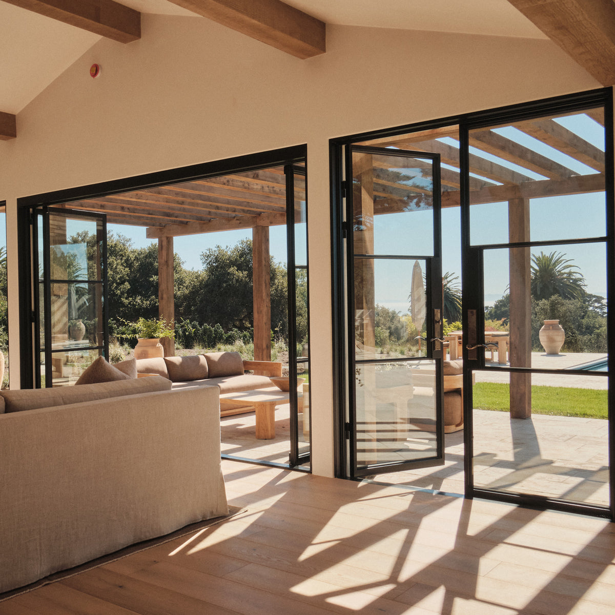 airy seaside living room featuring double steel doors and bi-fold with rocky mountain hardware