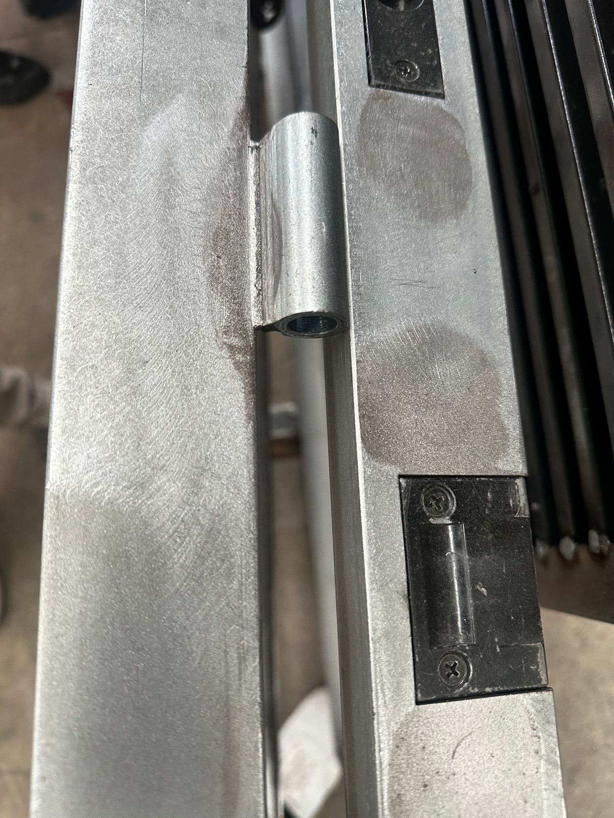 Closeup of unfinished steel frame with hinges and roller catch