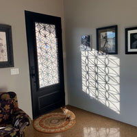 Single entryway door with a panel of glass behind iron detailing.