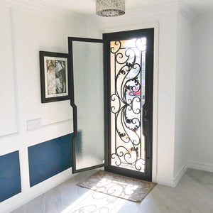 Single entryway door with a thick iron frame and a full panel of glass behind an intricate iron design. Door is thermally broken to protect from extreme weather.